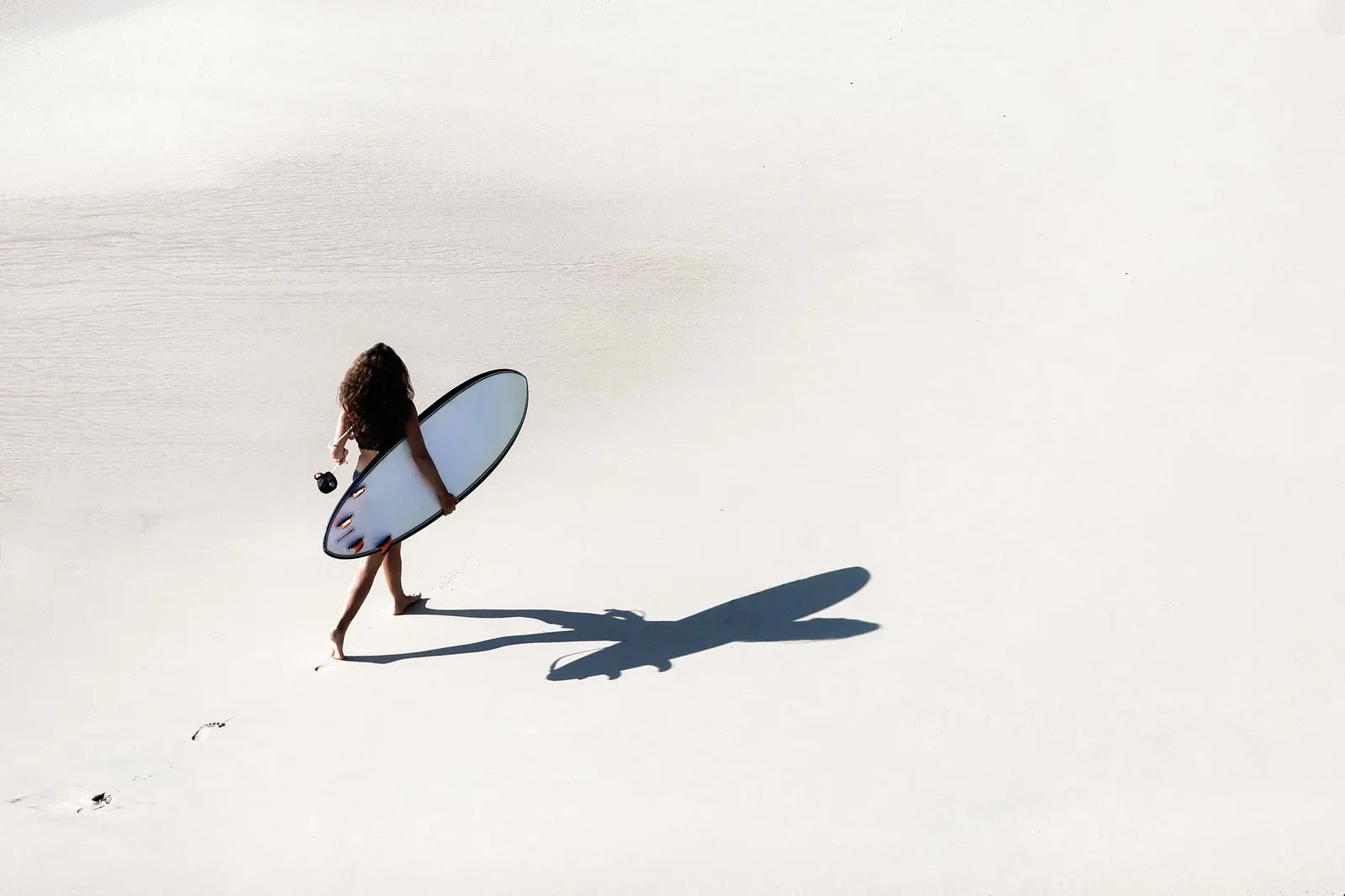 Surfer walking across the beach carrying a surfboard